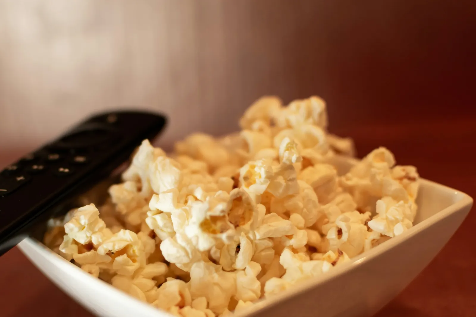 Bol de pop-corn et télécommande posés sur une table, prêts pour un match à la télé