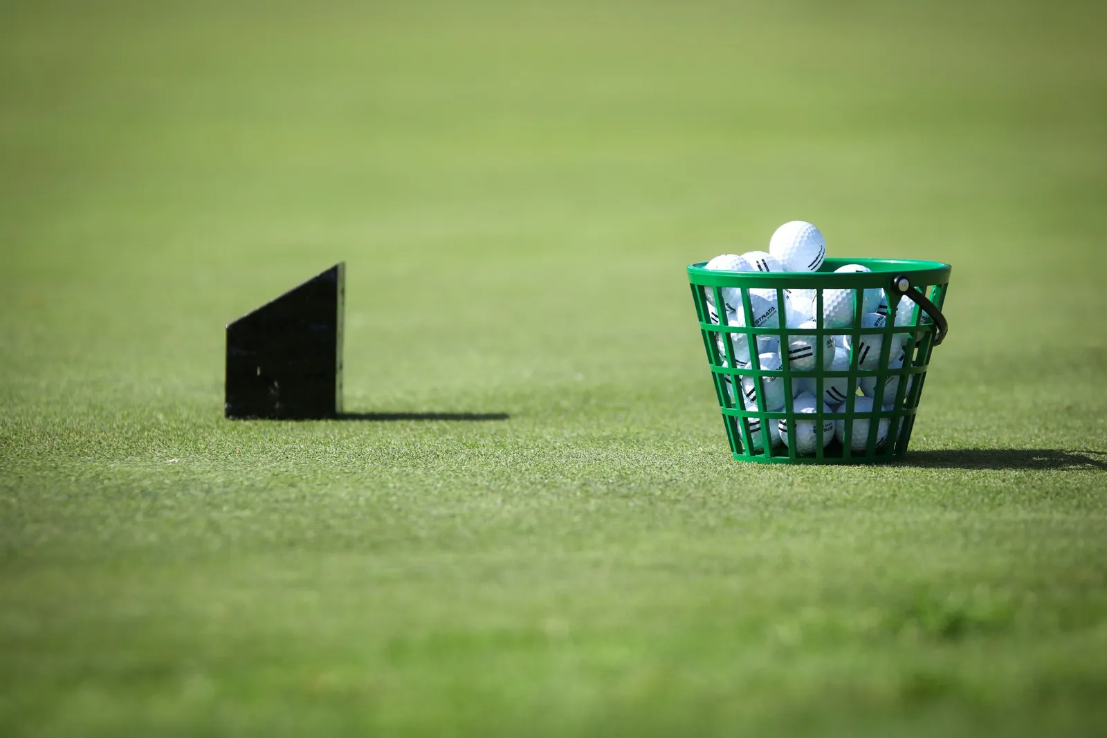 Panier de balles de practice posé sur un tapis d'herbe au practice de golf
