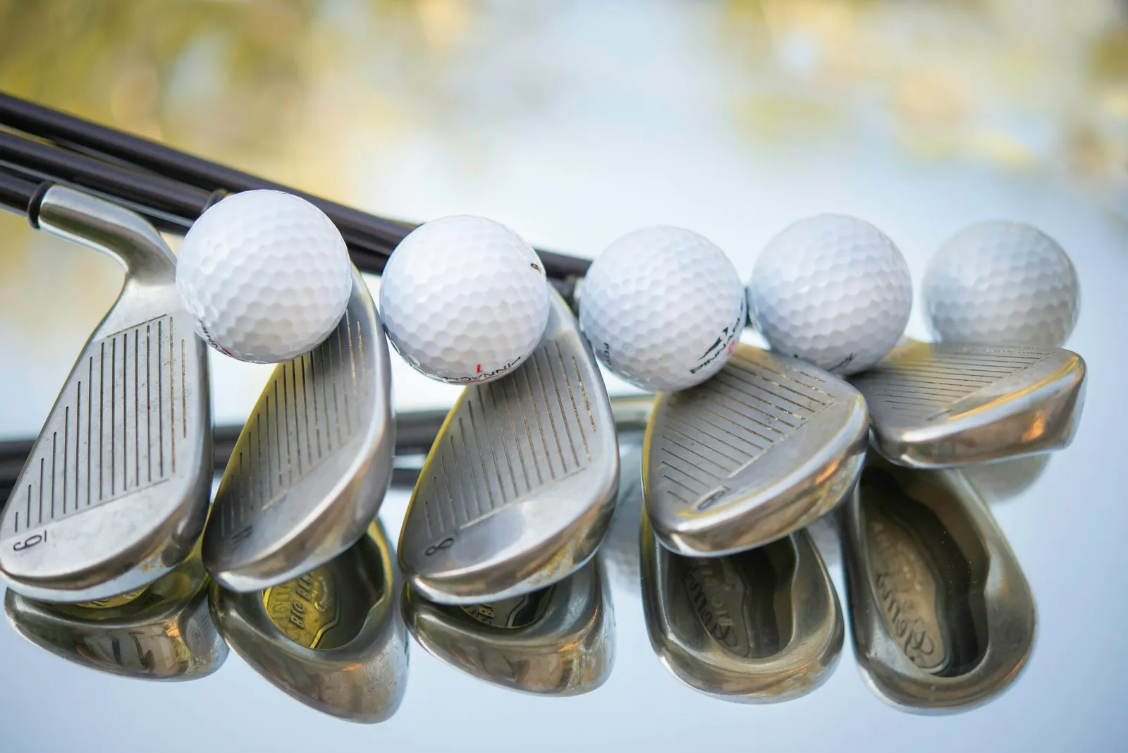Rangée de fers de golf portant chacun une balle blanche