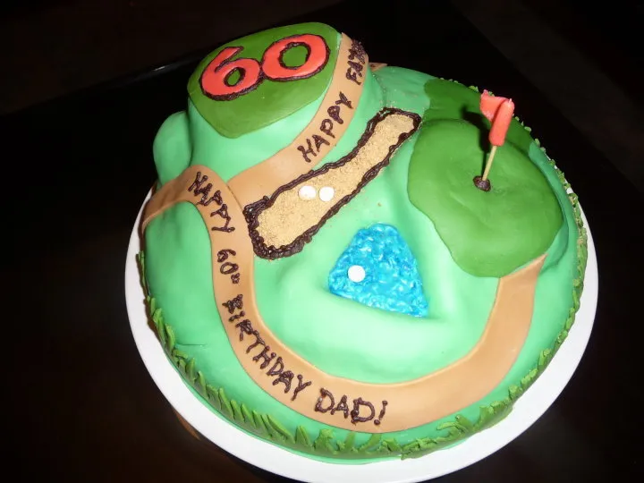 Gâteau d'anniversaire vert en forme de parcours de golf, avec un green et son drapeau rouge, un bunker, un obstacle d'eau et un grand chiffre 60